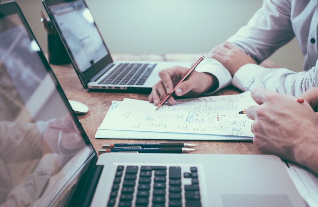 一位专业人士正指着白板上的商业增长图表，展现了团队正在进行战略规划和数据分析的场景，象征着通过数据驱动实现业务目标。