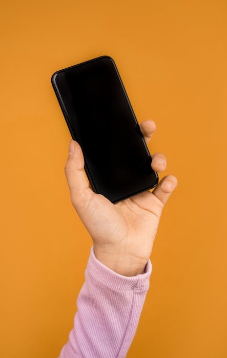 一位女性创业者在她的工作室里开心地看着手机上显示的业务增长数据